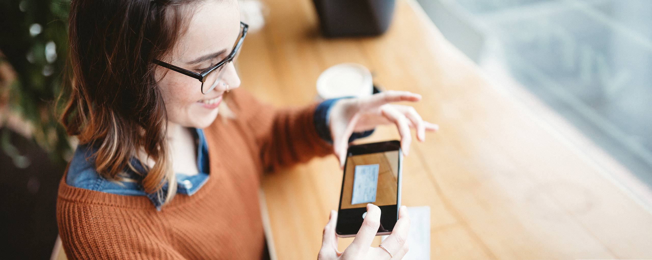 A woman takes a picture of a check so she can deposit it without visiting a branch, just one benefit of online banking services.