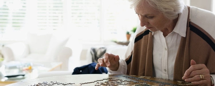 A woman sits at her kitchen table and puts together a puzzle, a relaxing distraction as she considers whether to invest in a CD.