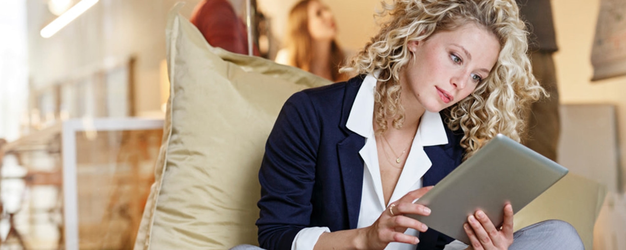 A sitting woman uses her tablet to compare checking accounts, savings accounts, money market accounts and certificates of deposits (CDs).