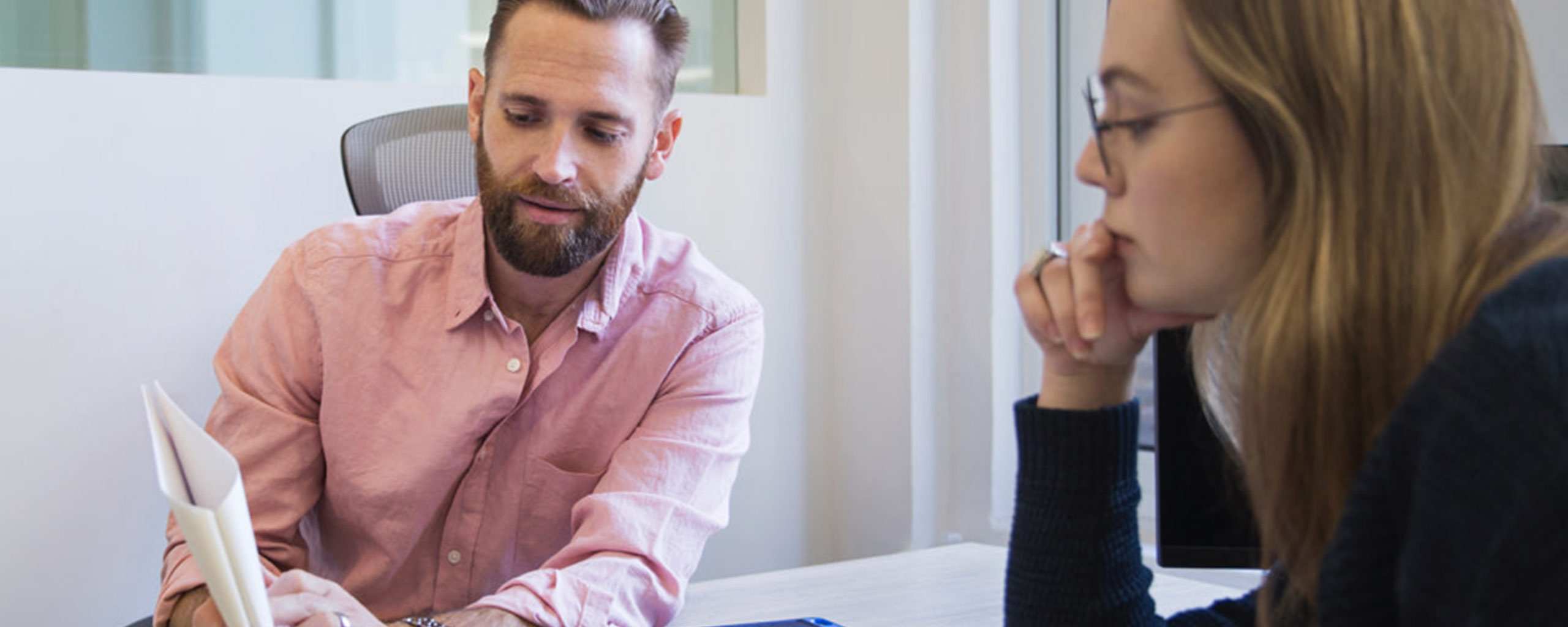 A bearded man and a woman in glasses discuss the benefits of a savings account.