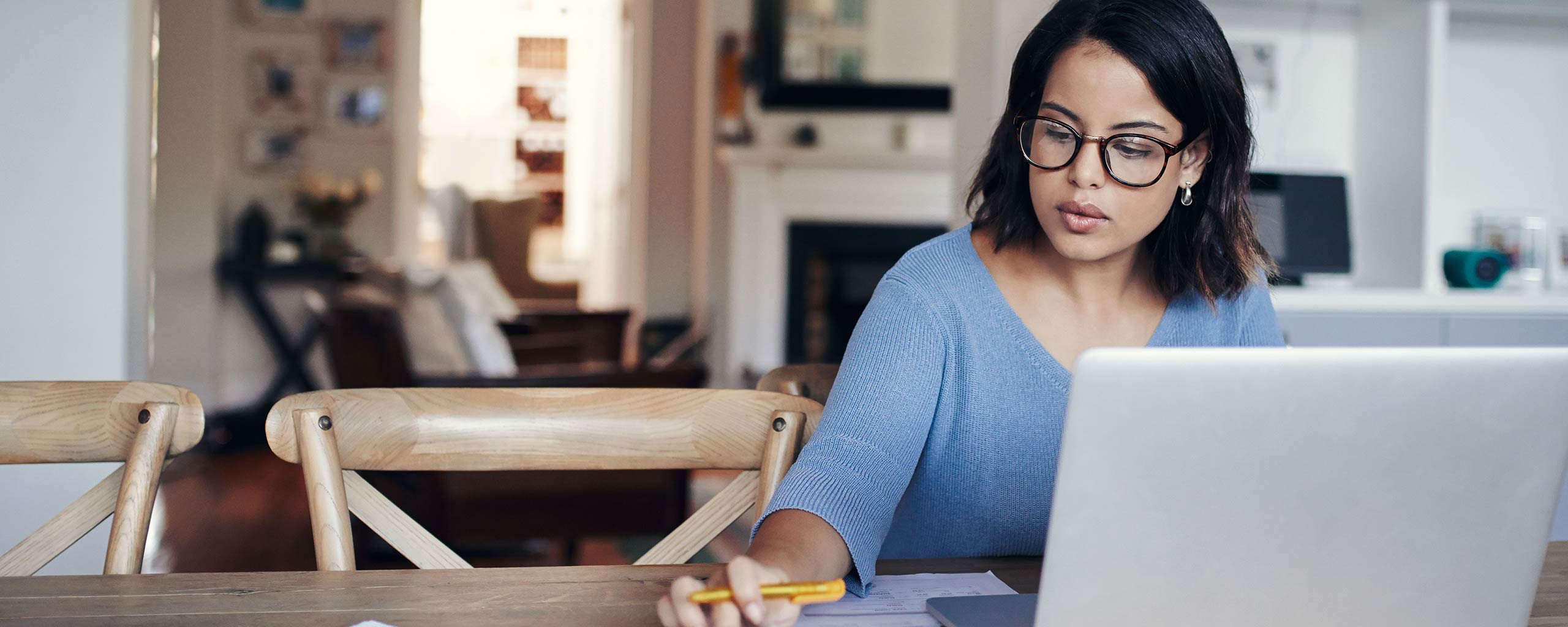 A woman sits at her home computer and closes her bank account.