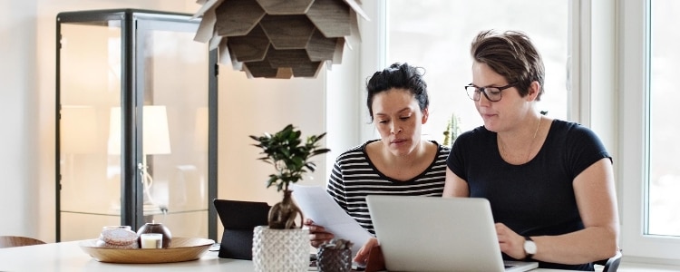 Two women work together at a laptop and apply for a personal loan.