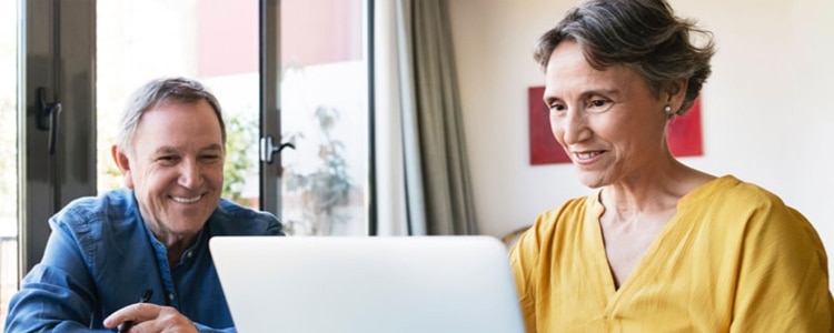 A middle-aged couple sits at a laptop and explores whether an IRA CD is right for them.