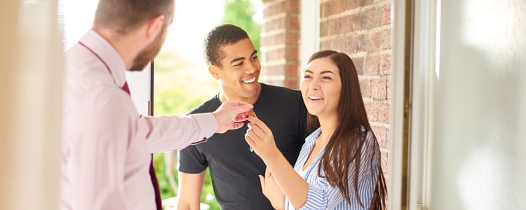 A landlord hands apartment keys to a couple who used a cashier’s check to pay their security deposit.