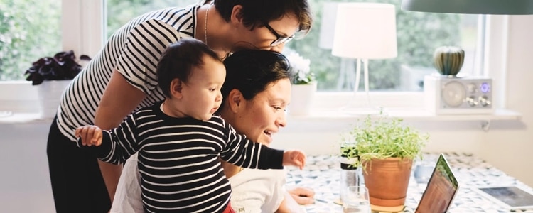 New parents sit at a kitchen table with their toddler and figure out ways to budget and save while money is tight.