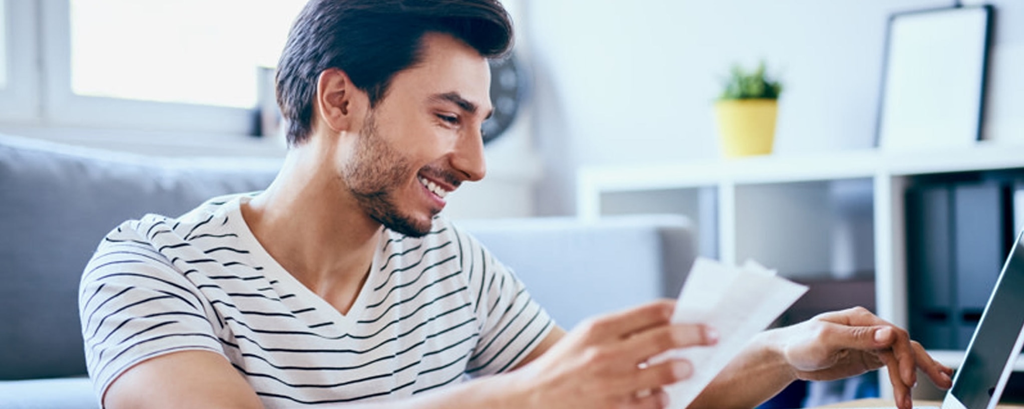 Young man reviews receipts against his online bank account looking for ways to save.