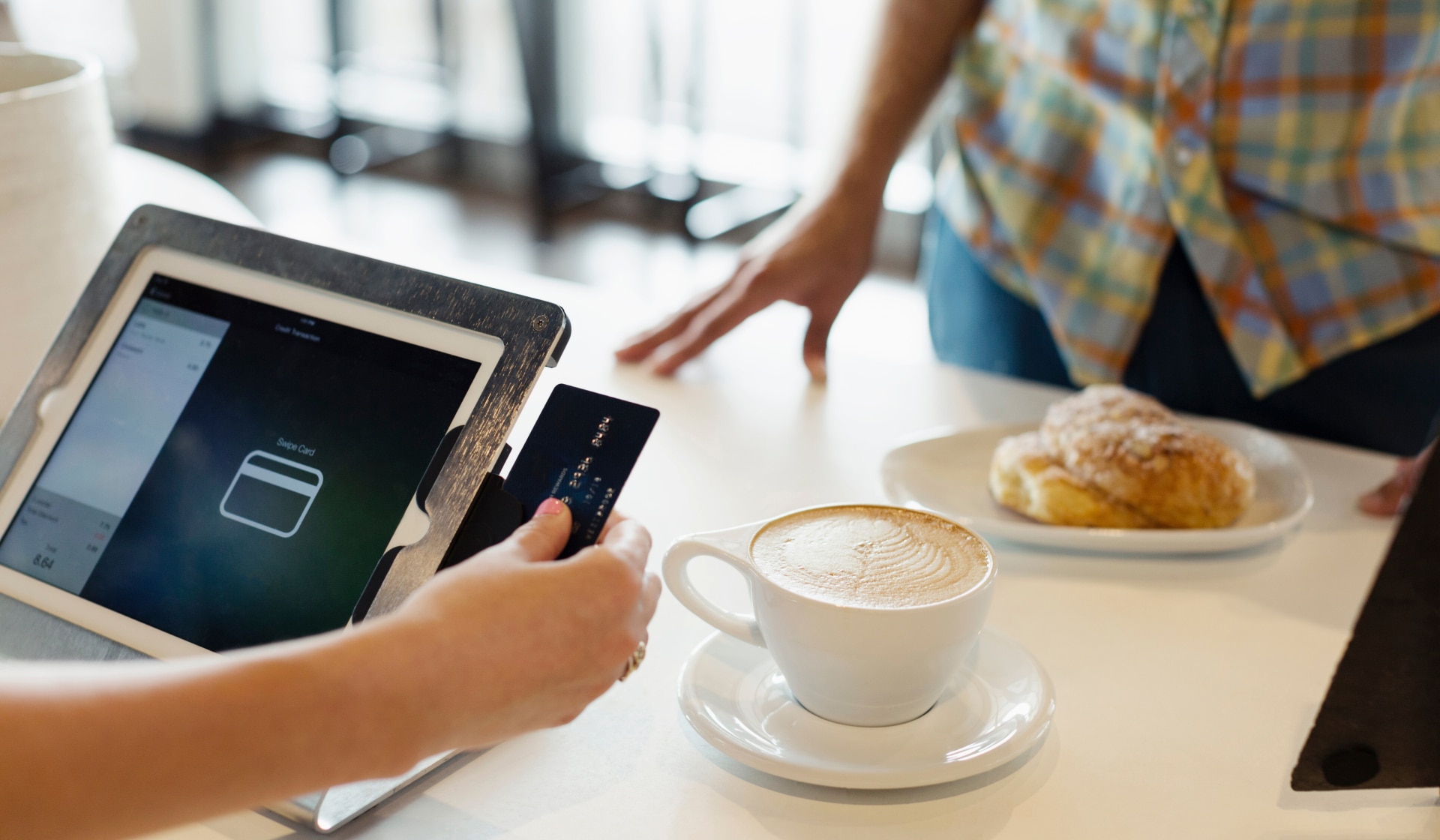 card sliding into tablet card reader with cappuccino to the right