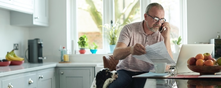 A businessperson reviewing documentation at the table while on the phone