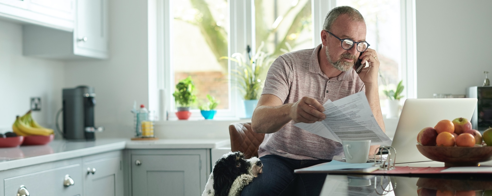 A businessperson reviewing documentation at the table while on the phone