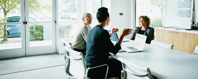 Three women in a face-to-face meeting with laptops open