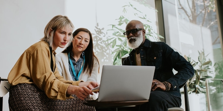 Three people look intently at a laptop screen