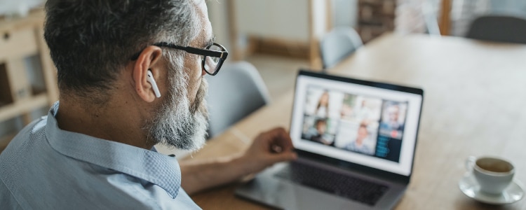 Man with glasses conducting virtual meeting on laptop