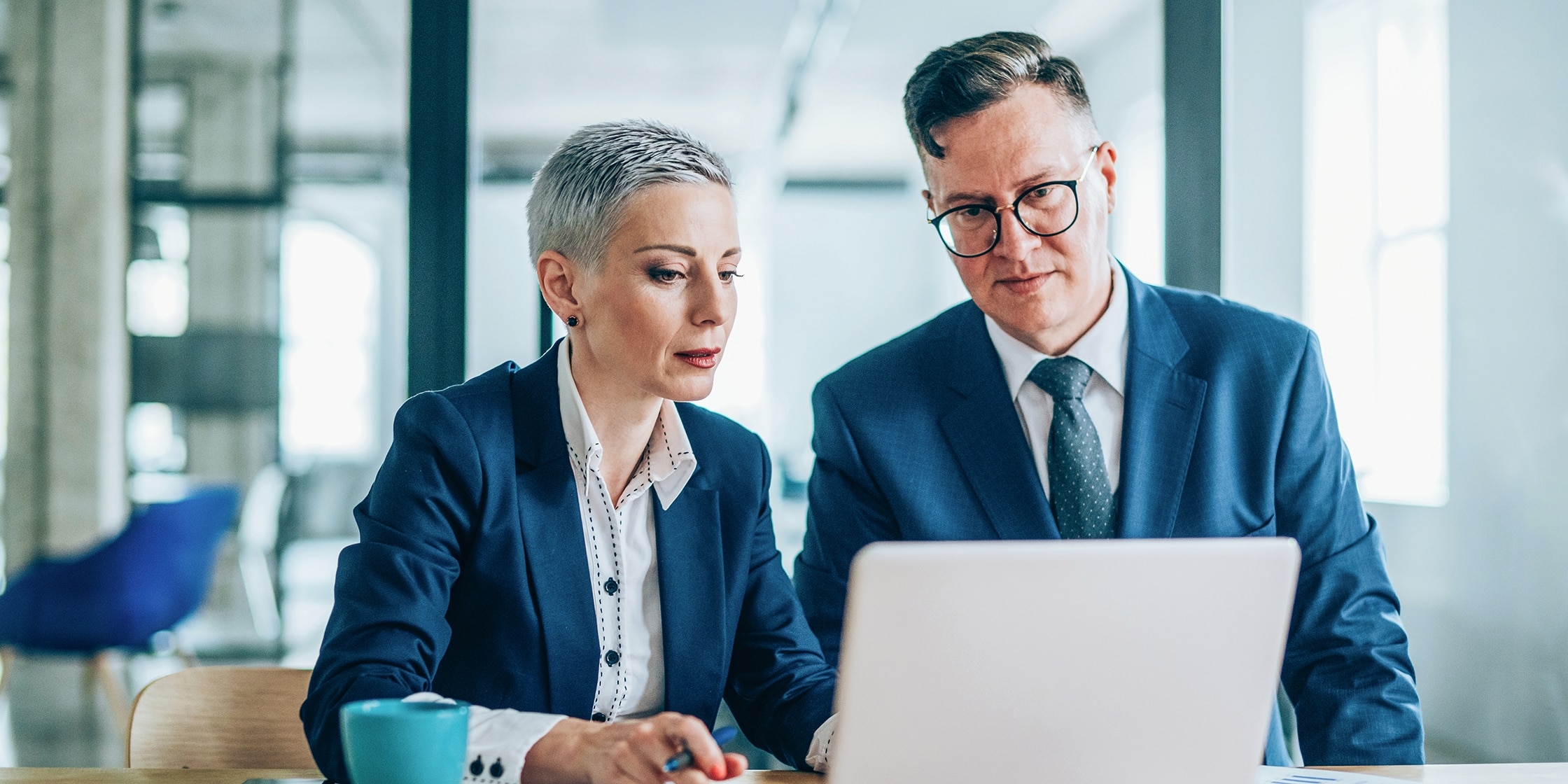 Woman and man, seated, reviewing something on a laptop