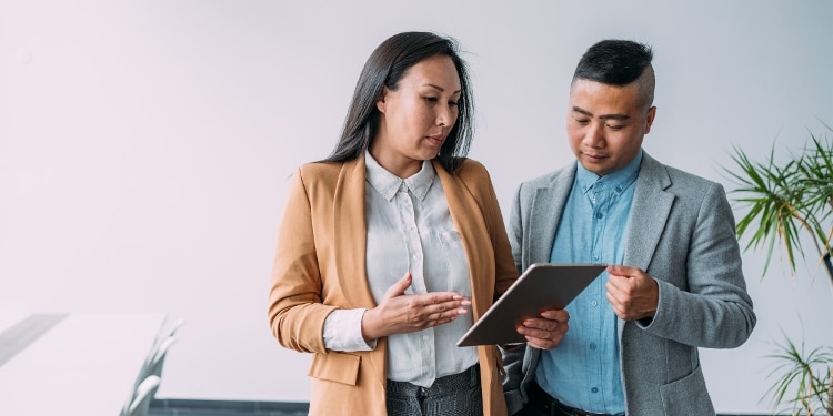 Woman and man, standing, look at a tablet in an office setting