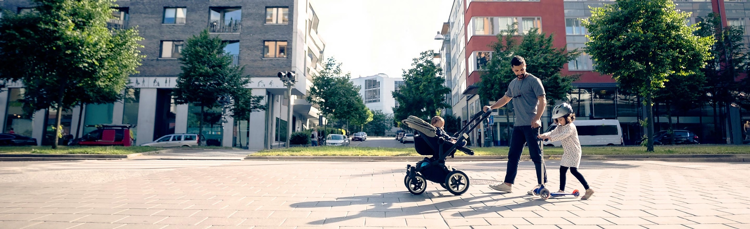 Dad pushing a stroller in front of buildings constructed using LIHTC funding