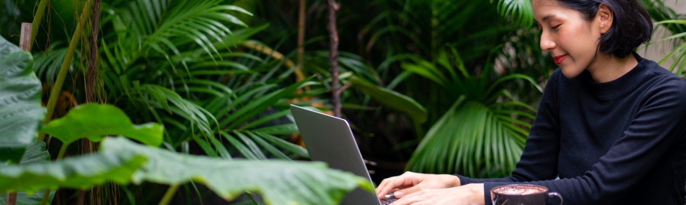 women working at on her laptop surrounded by plants