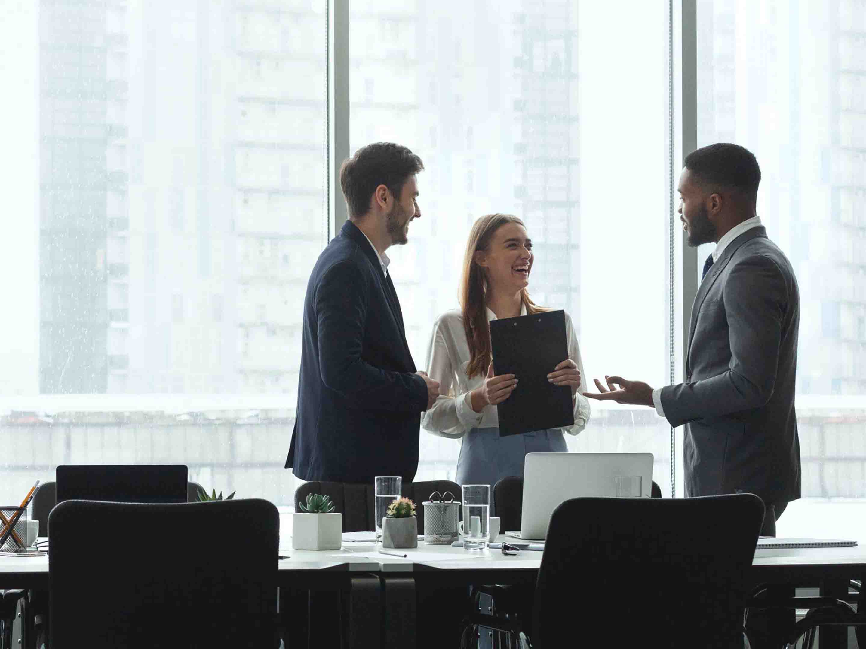 Two men and one women talking in business attire