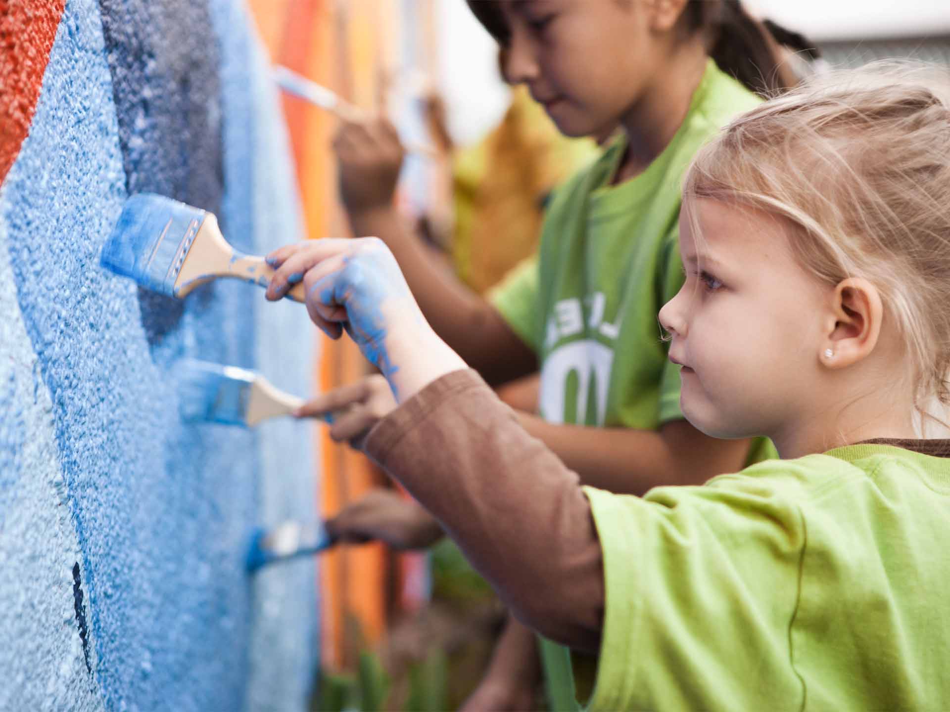 young child painting a mural outside