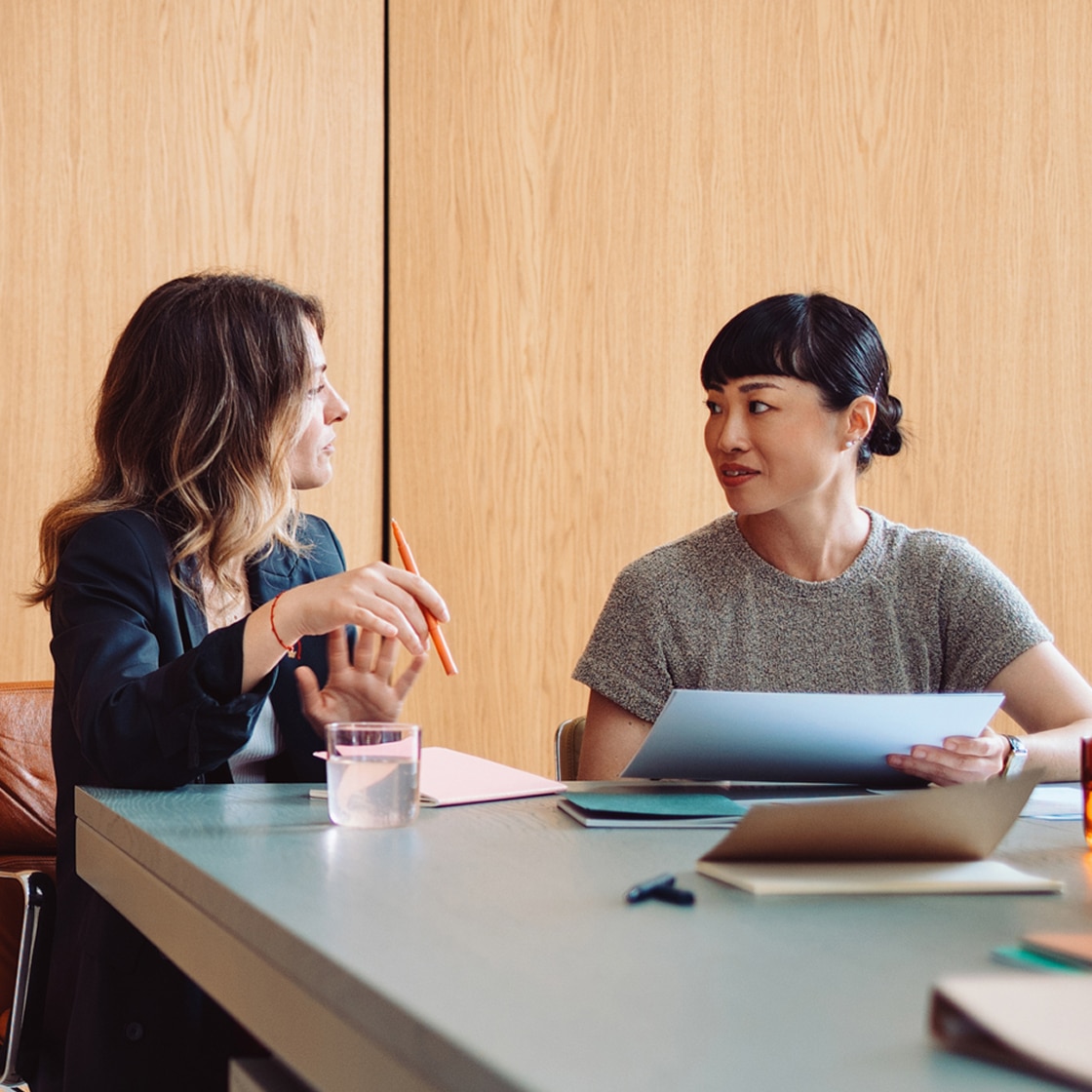 Two people talking in a business setting with laptops