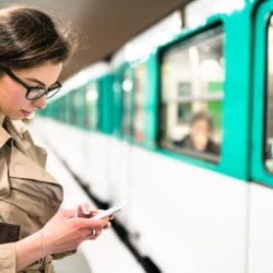 Woman on her phone stands next to a commuter train.