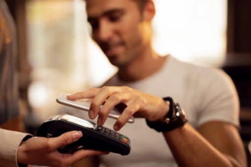 Man uses mobile phone to tap to pay on credit card reader.