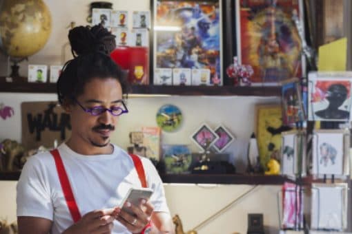 Young professional looks down at his mobile phone while inside a store.