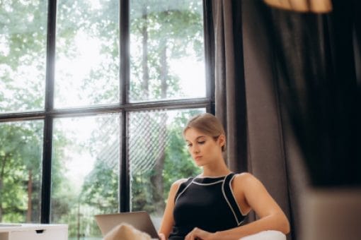 Woman sits on couch looking at computer.