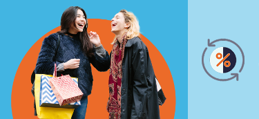 Two women laugh together as one of them holds shopping bags in her hand
