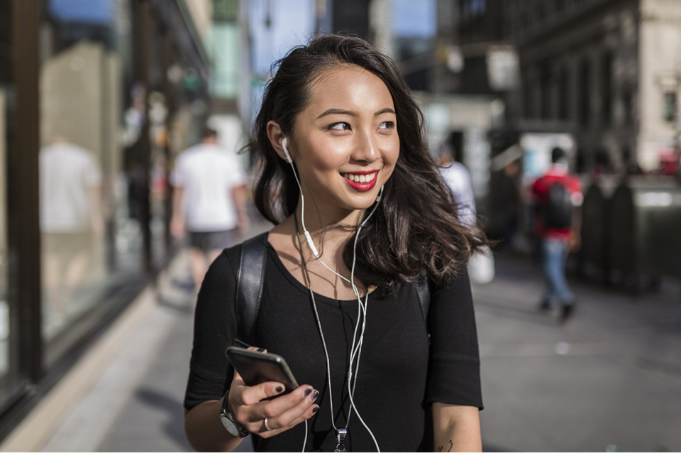 young woman walking and listening to music through headphones