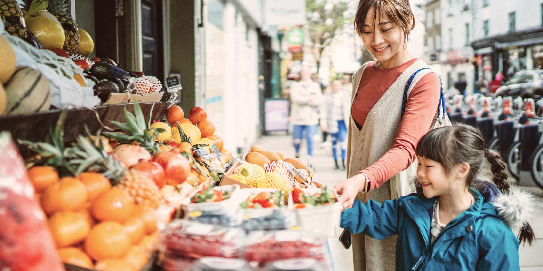 A woman uses her digital wallet on her smartphone to pay for her groceries at the farmers market.