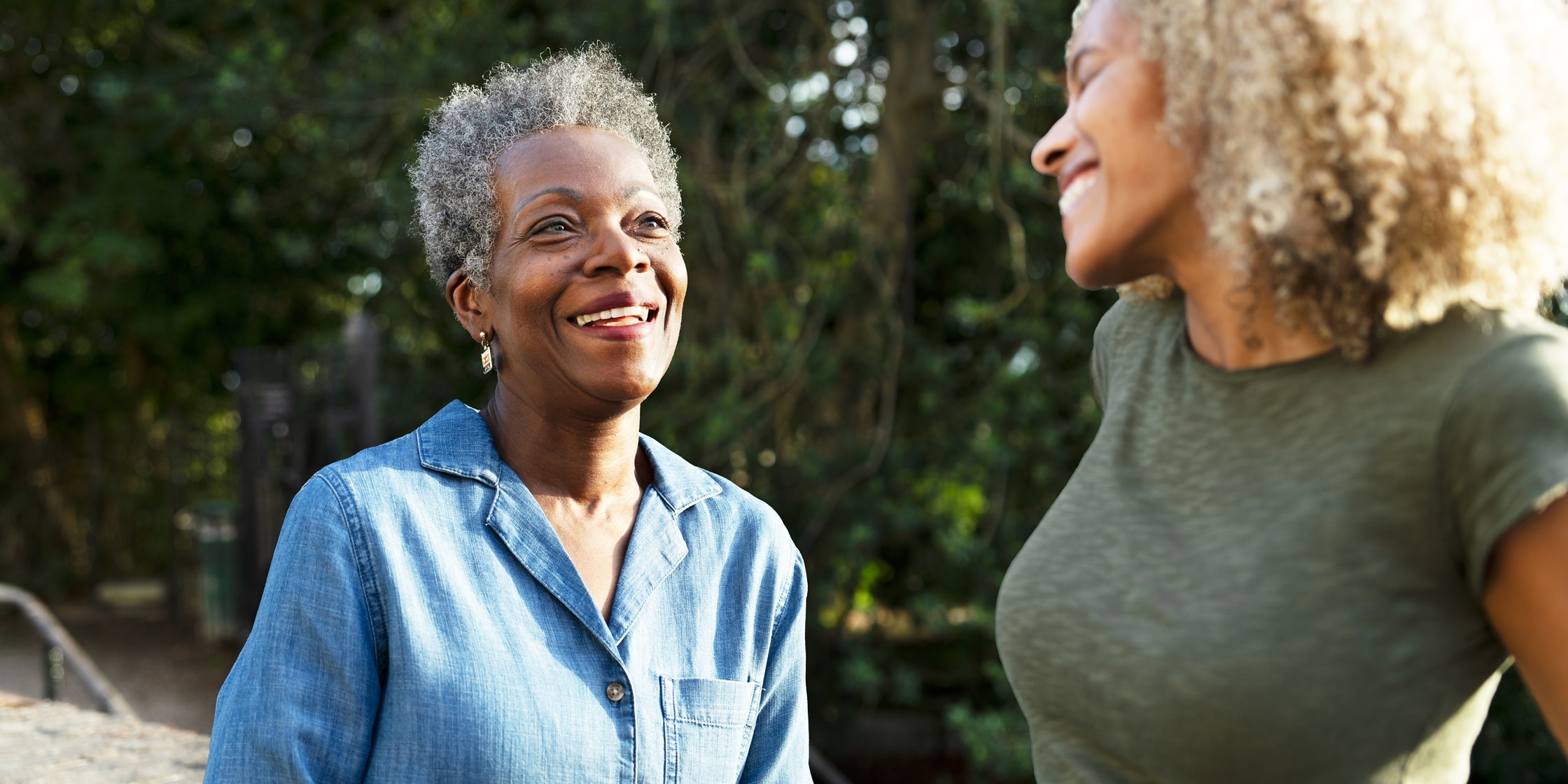 An older woman and a younger woman smile and talk to one another.