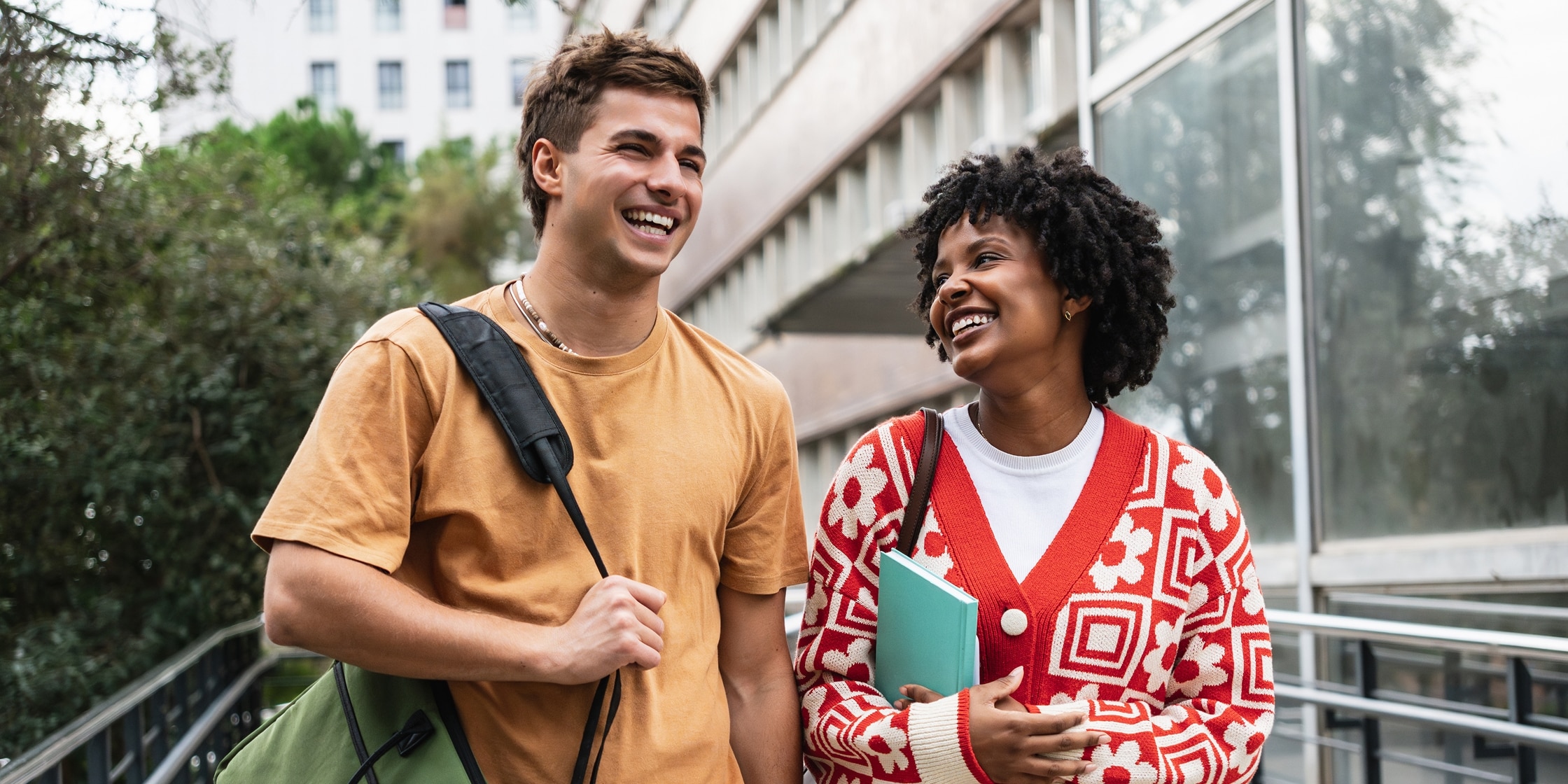 Two students walk outside chatting and smiling.