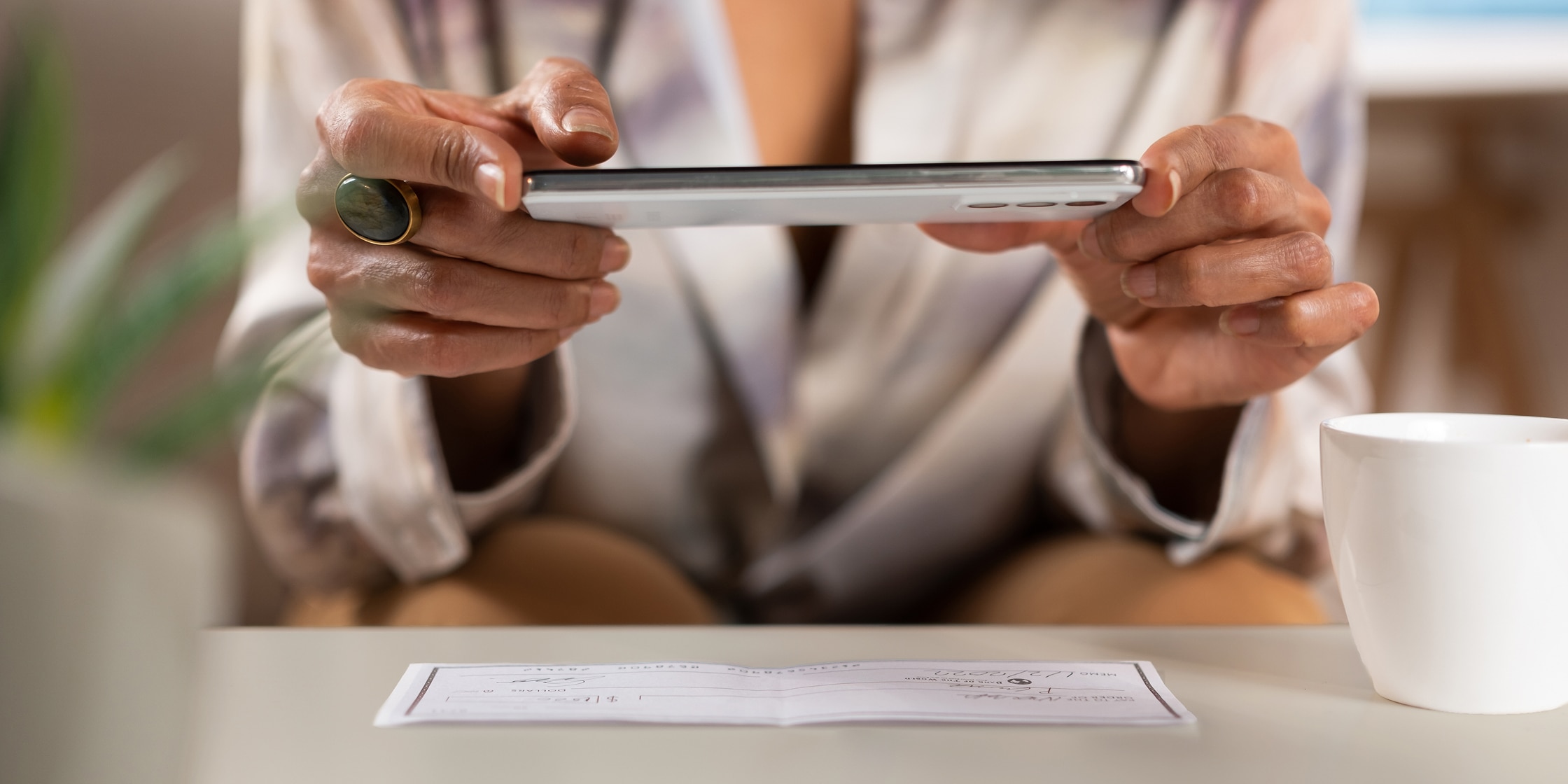 A woman uses her smartphone to take a photo of her check for deposit.