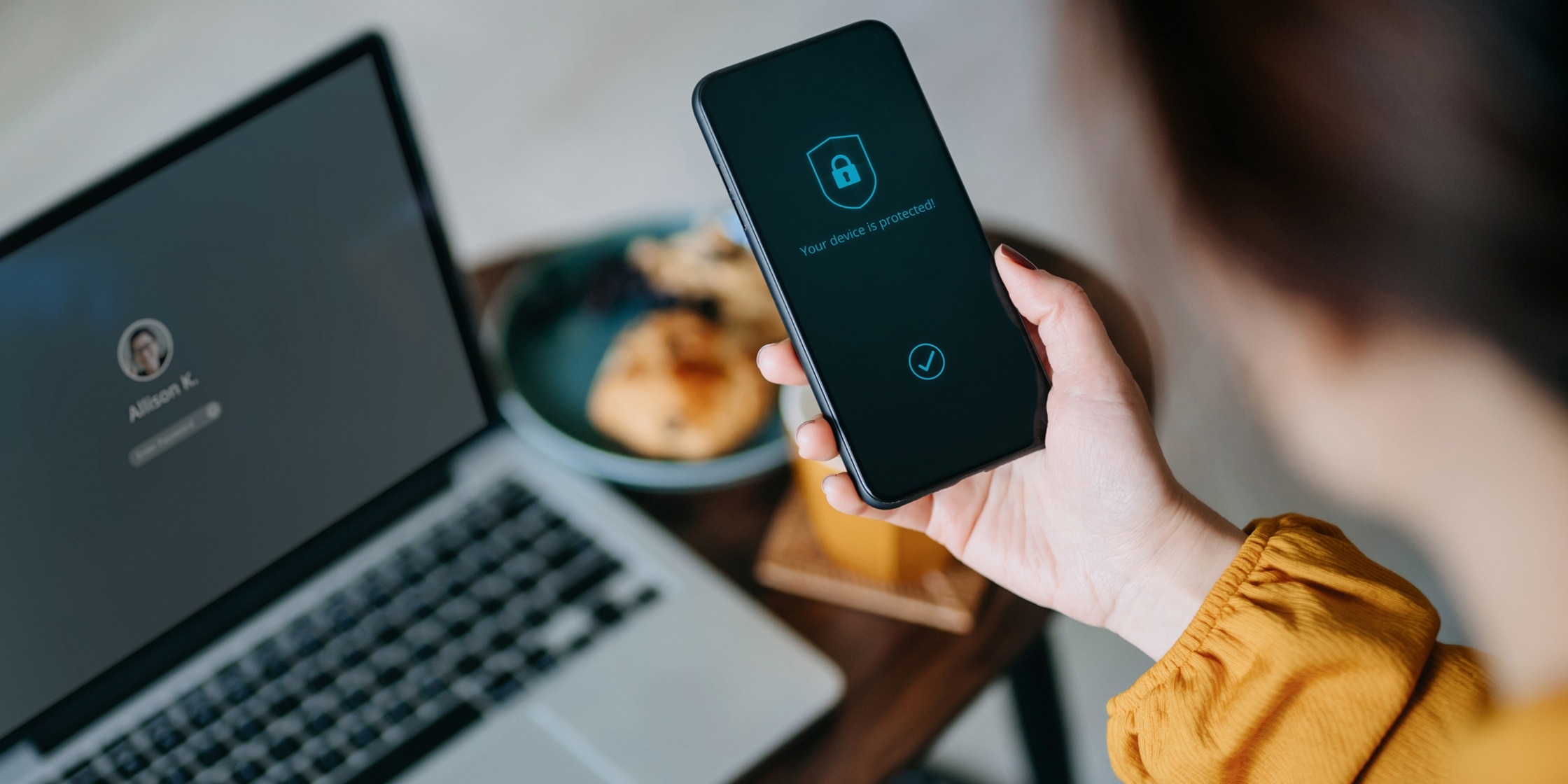 A woman looks at a message on her phone screen which reads, “Your device is protected!”