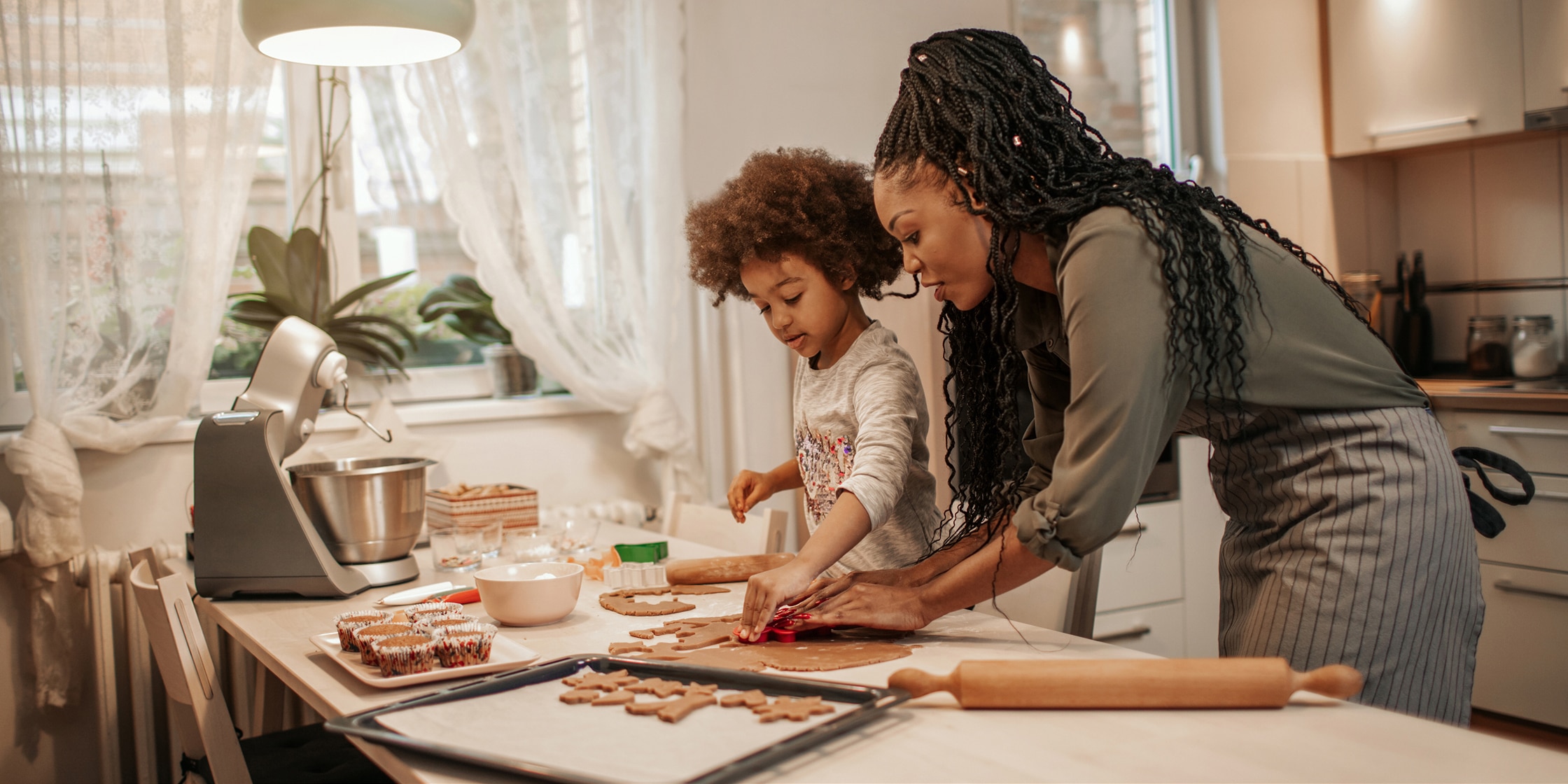 A mother and young son bake holiday cookies in a kitchen.