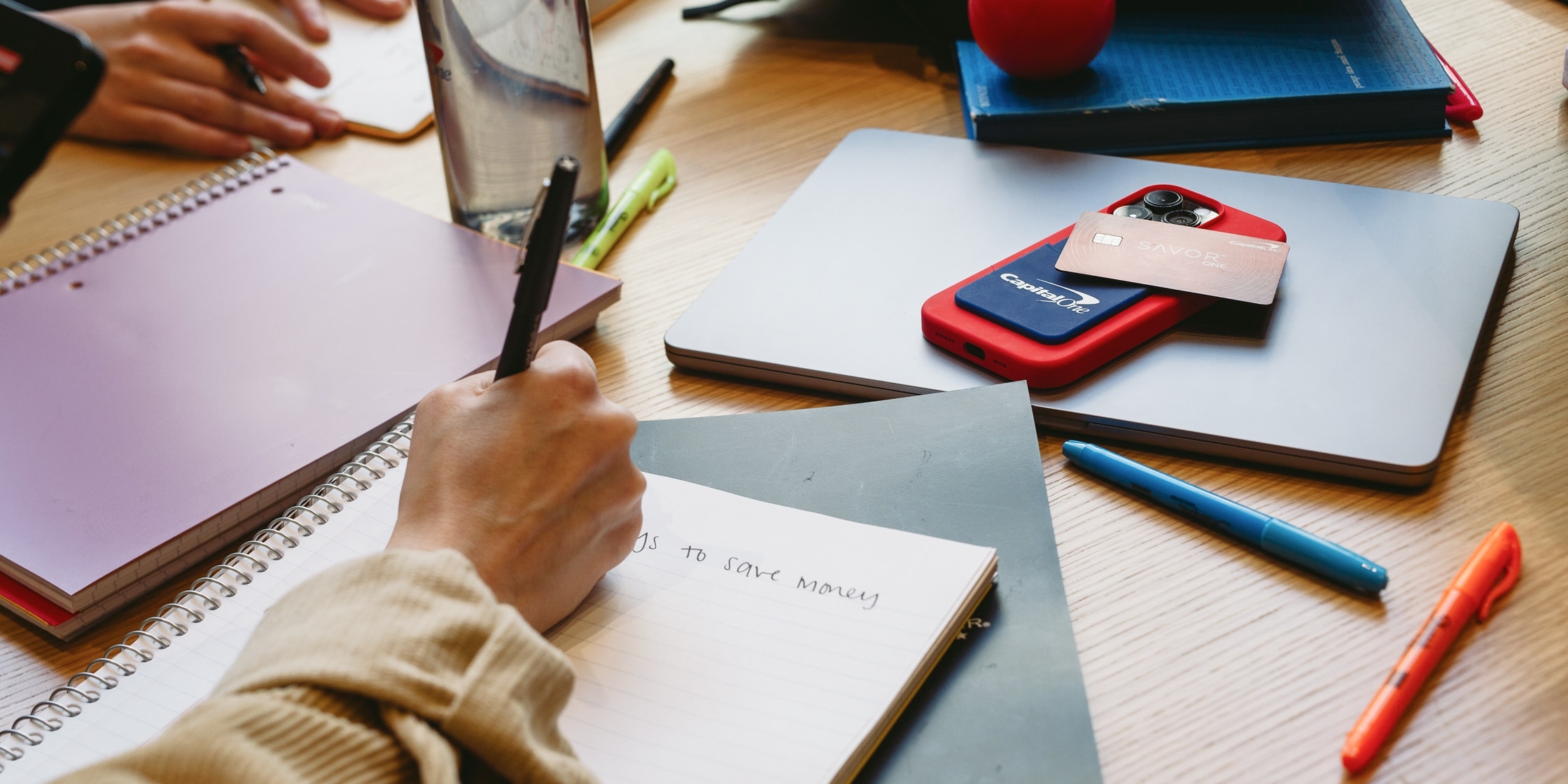 A person writes in a notebook about how to save money.