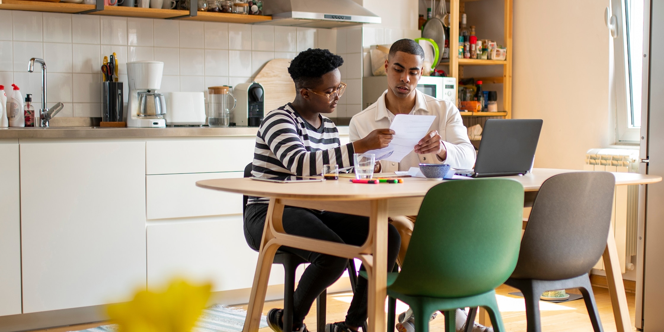 Two young people budget together at their living room table.