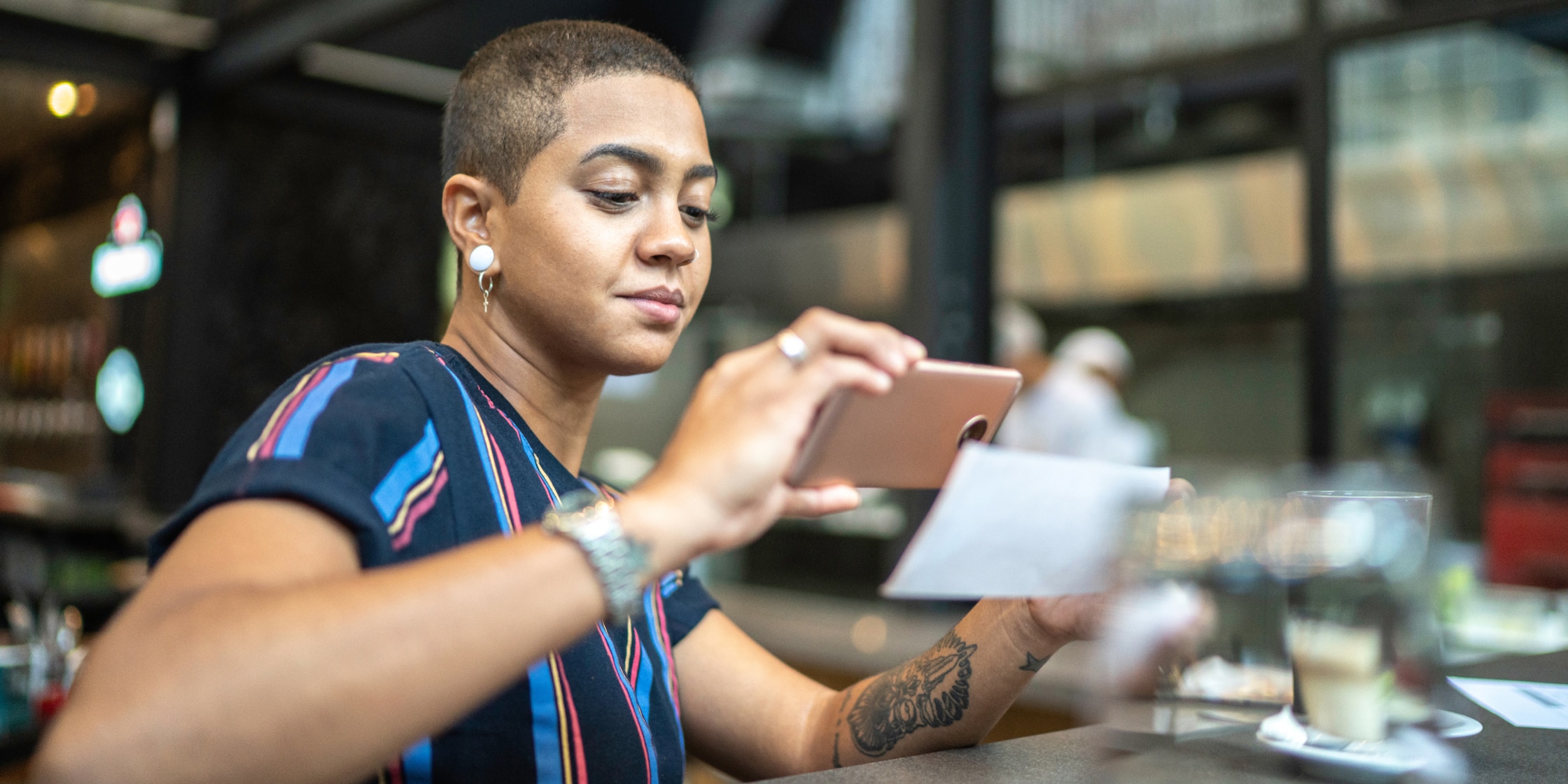 A young woman takes a photo of her receipt with her smartphone.