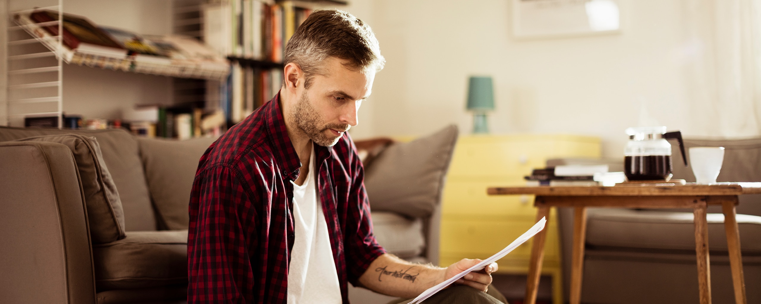 Man sitting and reading a letter at home.