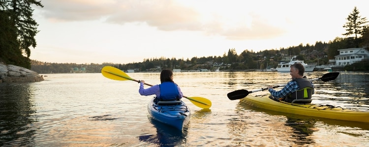 A couple enjoys their early retirement by kayaking on a lake.