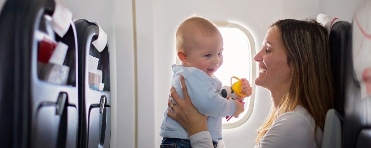 Smiling mother holds smiling baby during a flight.
