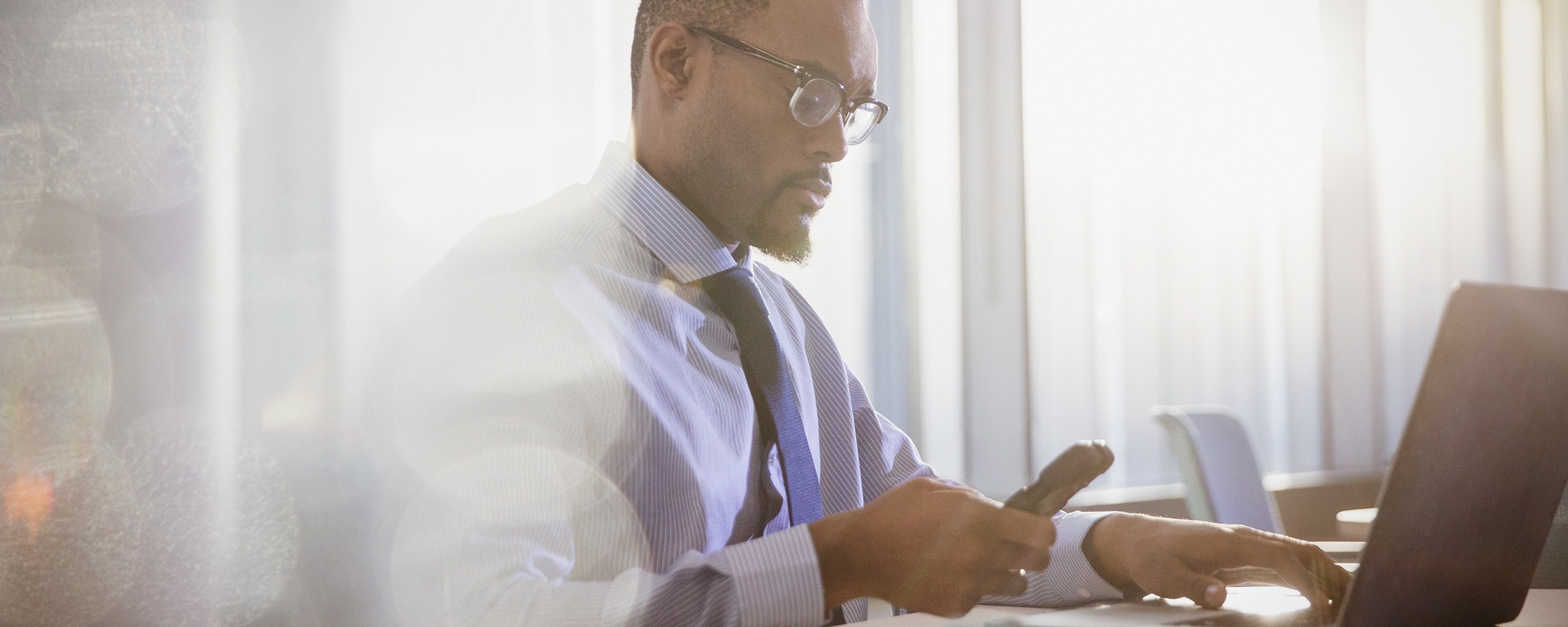 Man monitoring his credit on his phone and laptop.
