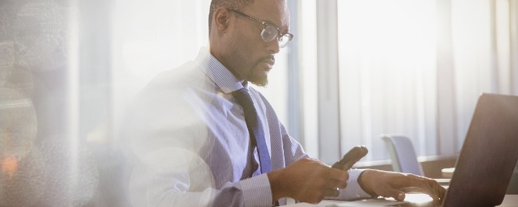 Man monitoring his credit on his phone and laptop.