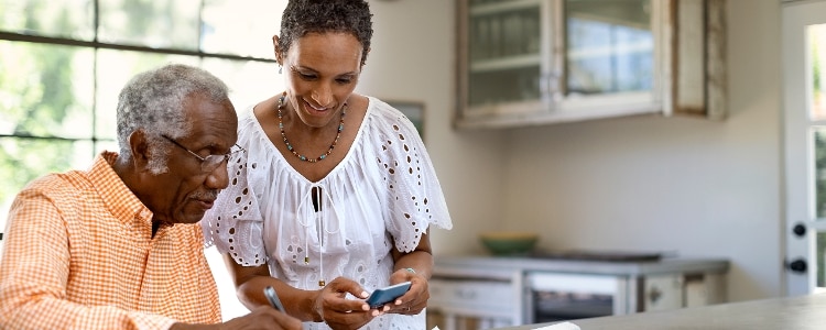A couple sits in a kitchen and researches credit counseling services.