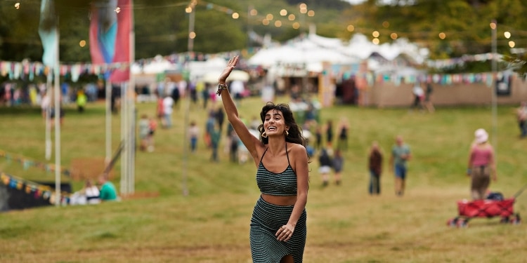 A person waving to a friend at a music festival.
