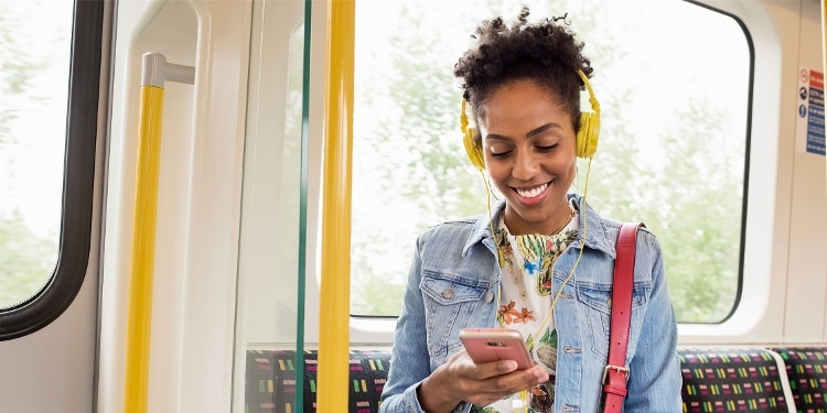 A person rides public transportation and uses their phone to check whether their money transfer is complete.