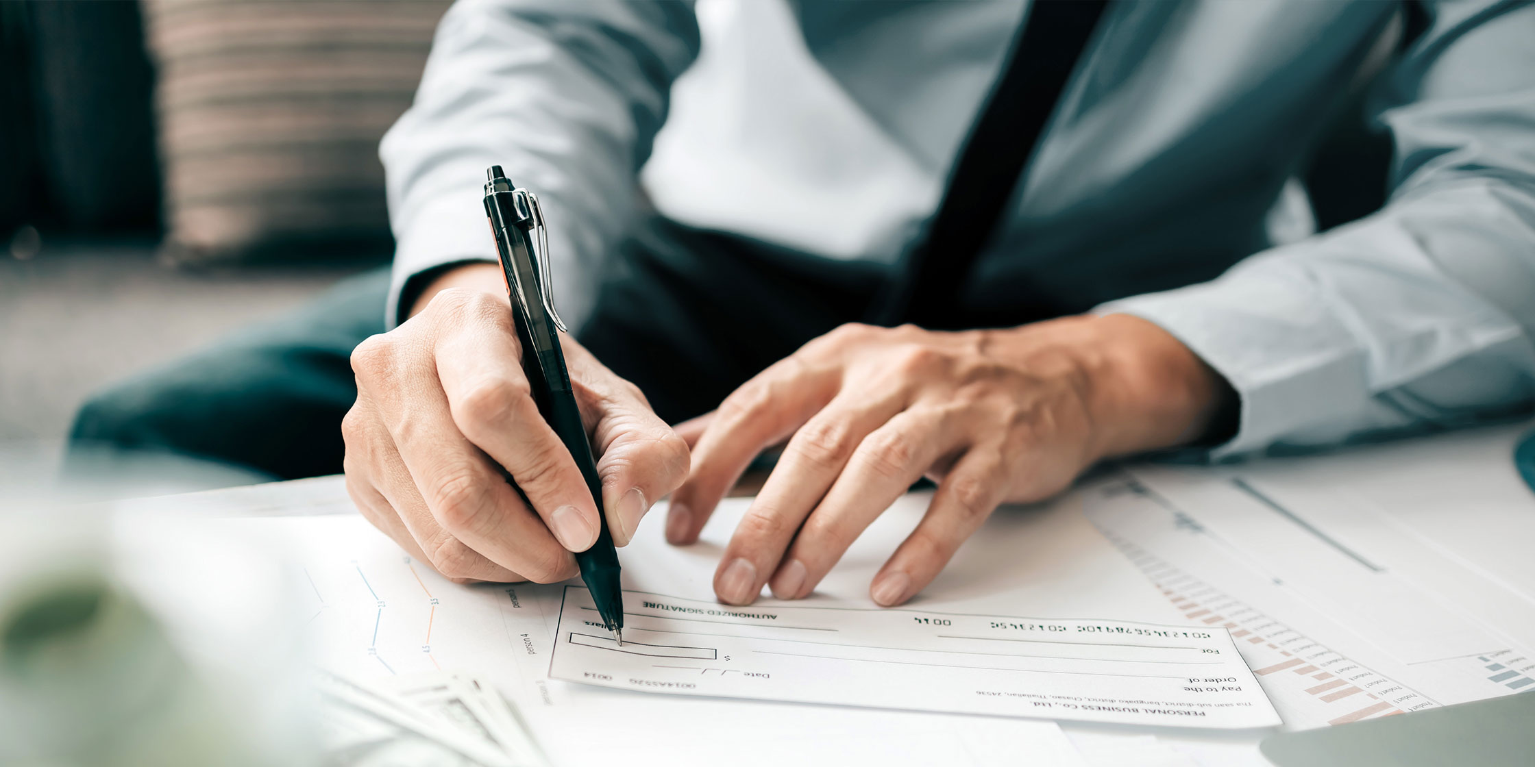 A person writes a check with a pen.