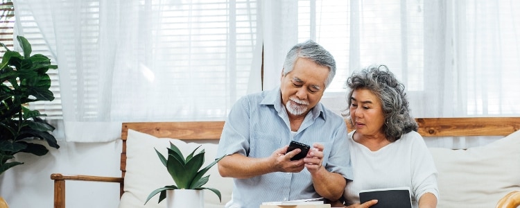 A photo of two people sitting on a sofa, reading on a mobile phone about credit scores and credit reports.