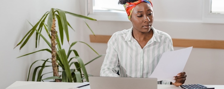 Young woman uses a laptop and a calculator to figure out her estimated tax payments.