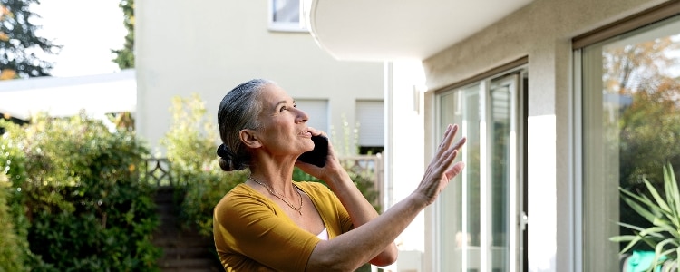 A person looks at the exterior of their home while talking on their cellphone.